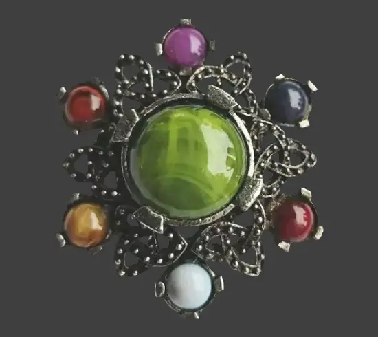 Brooch with Triquetra elements, symbolic trinity knot associated with earth, fire, and air, or mind, body, and soul. Multicolor glass cabochons, green gem, silver tone